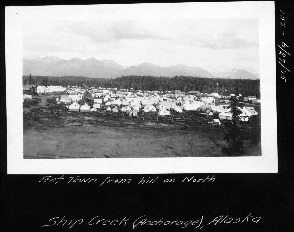 Black-and-white photograph looking down from a hill across the densely packed tent settlement at Ship Creek.